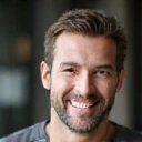 Retrato de un hombre de mediana edad con una barba cuidada y una sonrisa genuina.